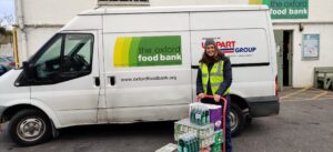 Volunteer beside donated supplies and an Oxford Foodbank van
