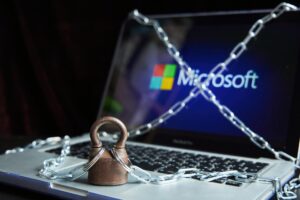Padlock and chain securing a laptop displaying the Microsoft logo