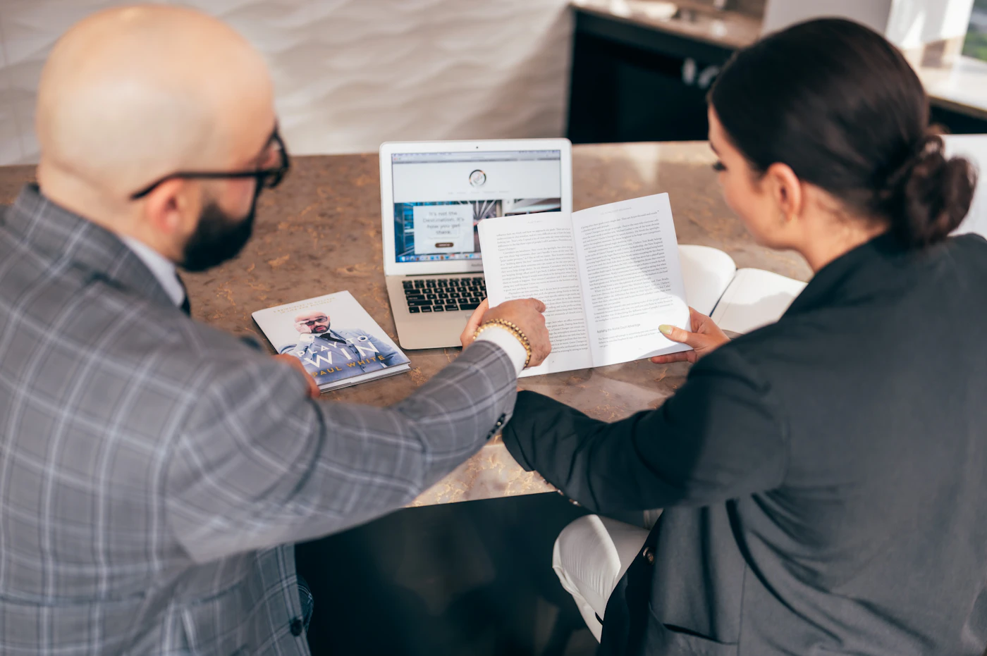 Two colleagues reviewing work together on a laptop